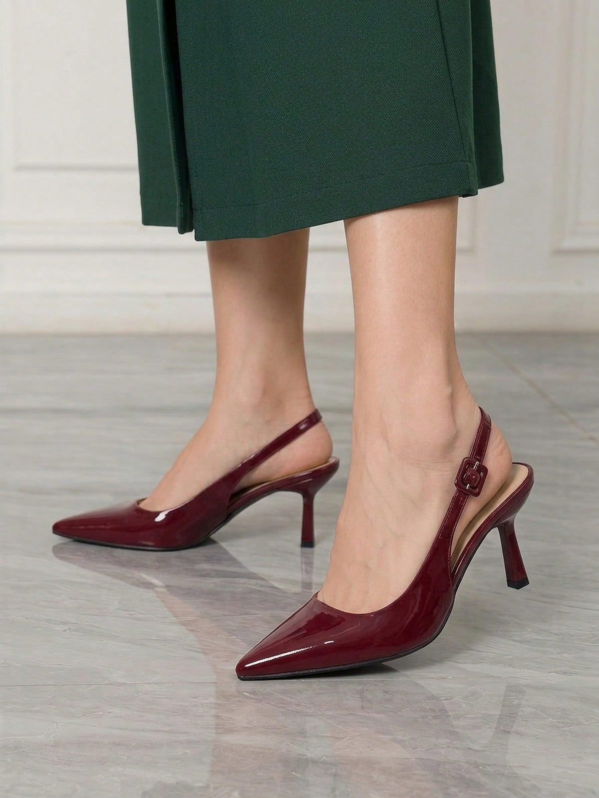 Women's pointed-toe high heel pumps in black mirror PU leather with an ankle strap, stiletto heel, and rhinestone buckle.