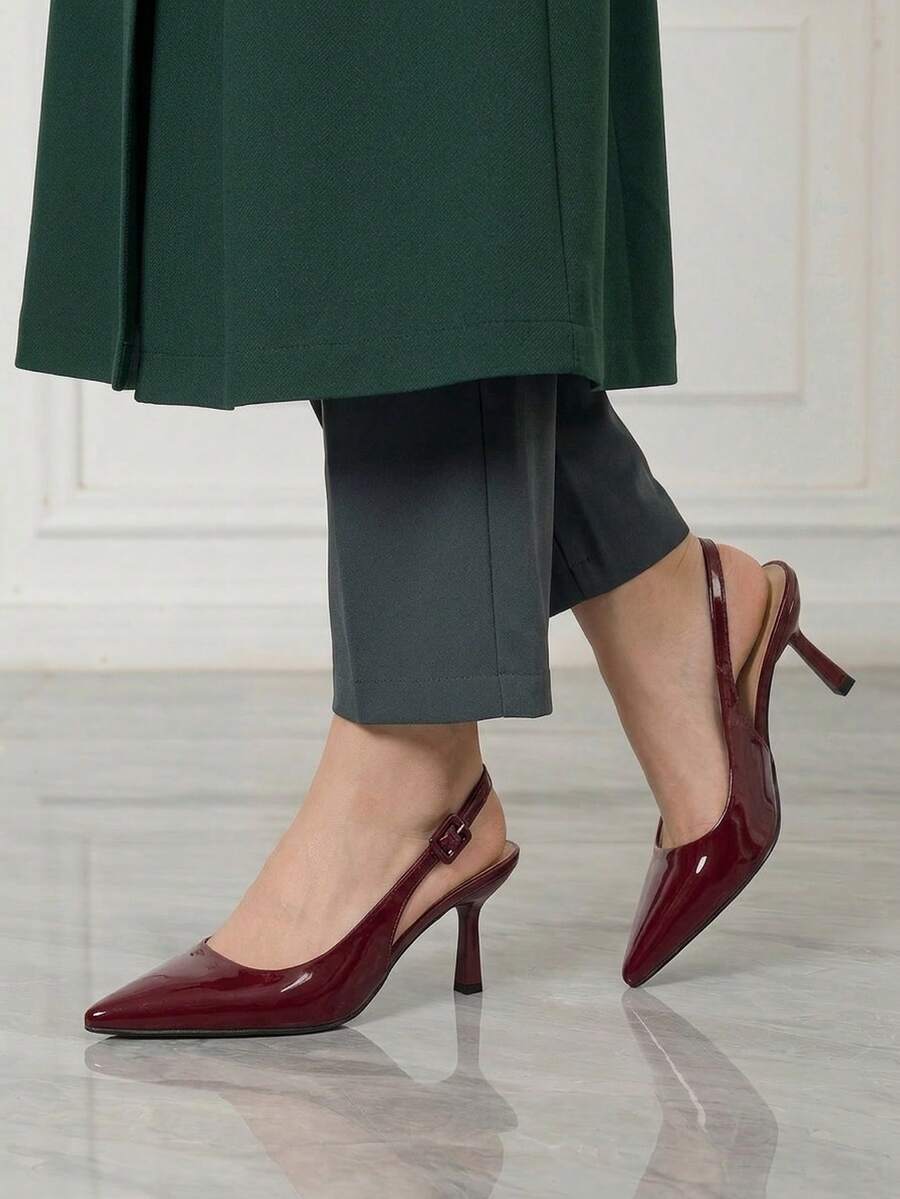 Women's pointed-toe high heel pumps in black mirror PU leather with an ankle strap, stiletto heel, and rhinestone buckle.