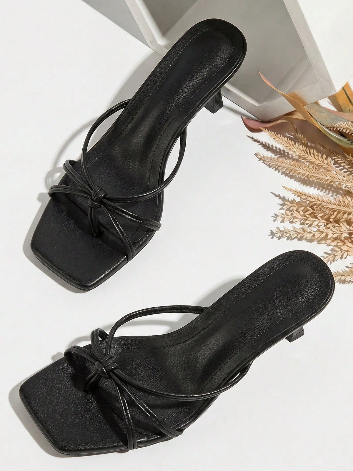 Women's slip-on mule heel sandals featuring knotted criss-cross strappy thong design, square open toe, and mid kitten heel.