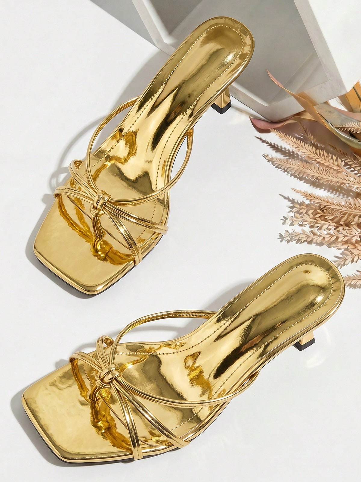 Women's slip-on mule heel sandals featuring knotted criss-cross strappy thong design, square open toe, and mid kitten heel.