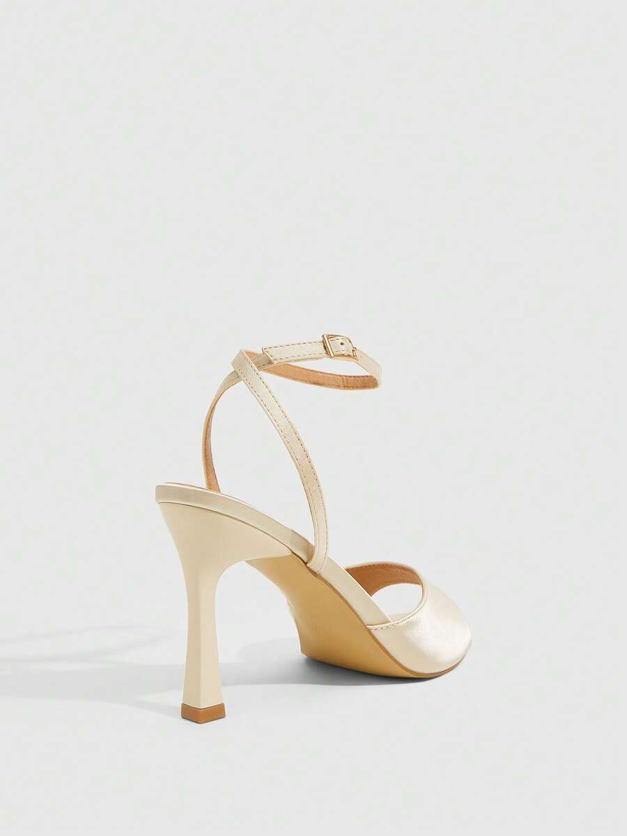Women's pointed peep toe high heel stilettos featuring cross ankle strap with buckle in black PU leather.