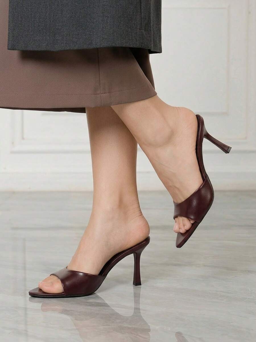 Women's high-heeled slippers in PU leather featuring an open plain toe, belt detail, and stiletto high heel with TPR outsole.