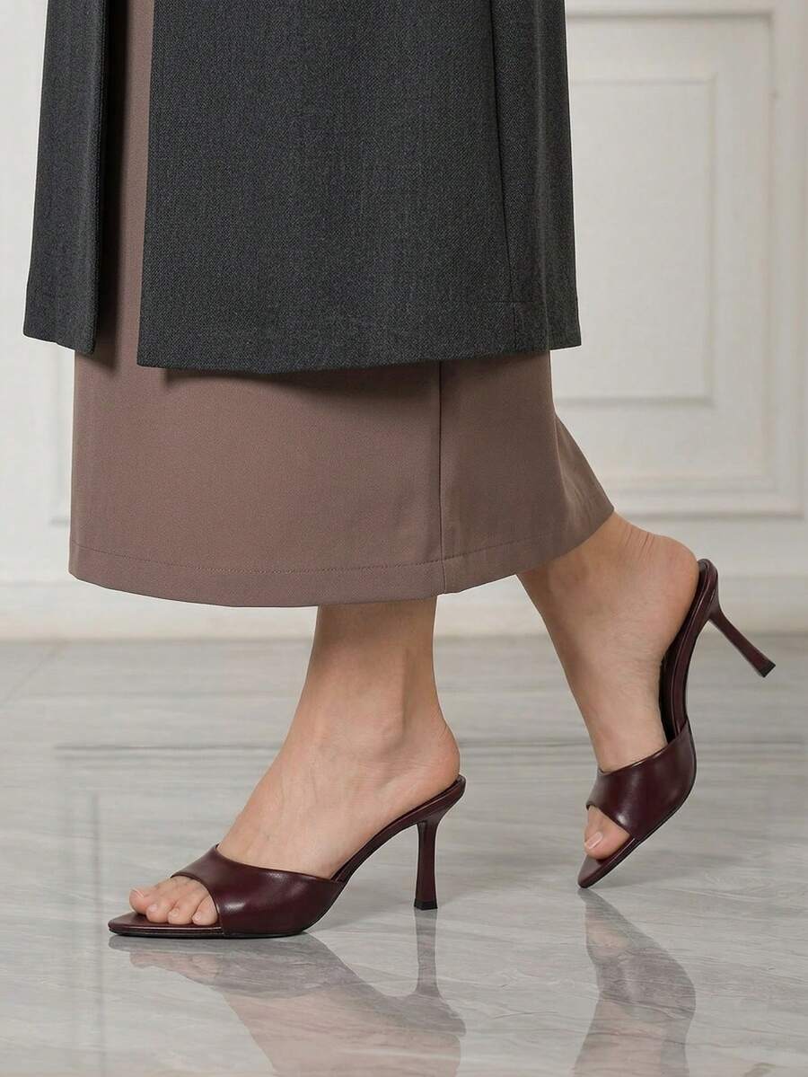 Women's high-heeled slippers in PU leather featuring an open plain toe, belt detail, and stiletto high heel with TPR outsole.
