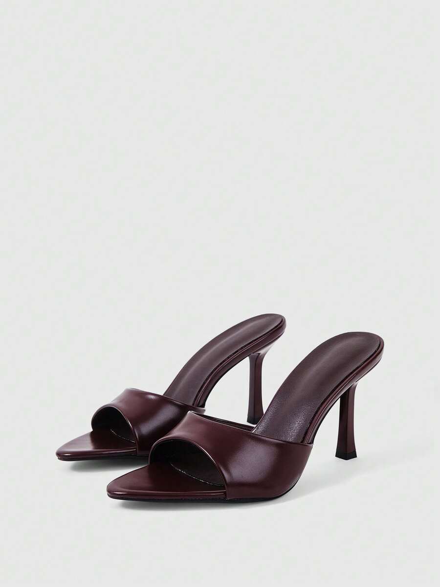 Women's high-heeled slippers in PU leather featuring an open plain toe, belt detail, and stiletto high heel with TPR outsole.