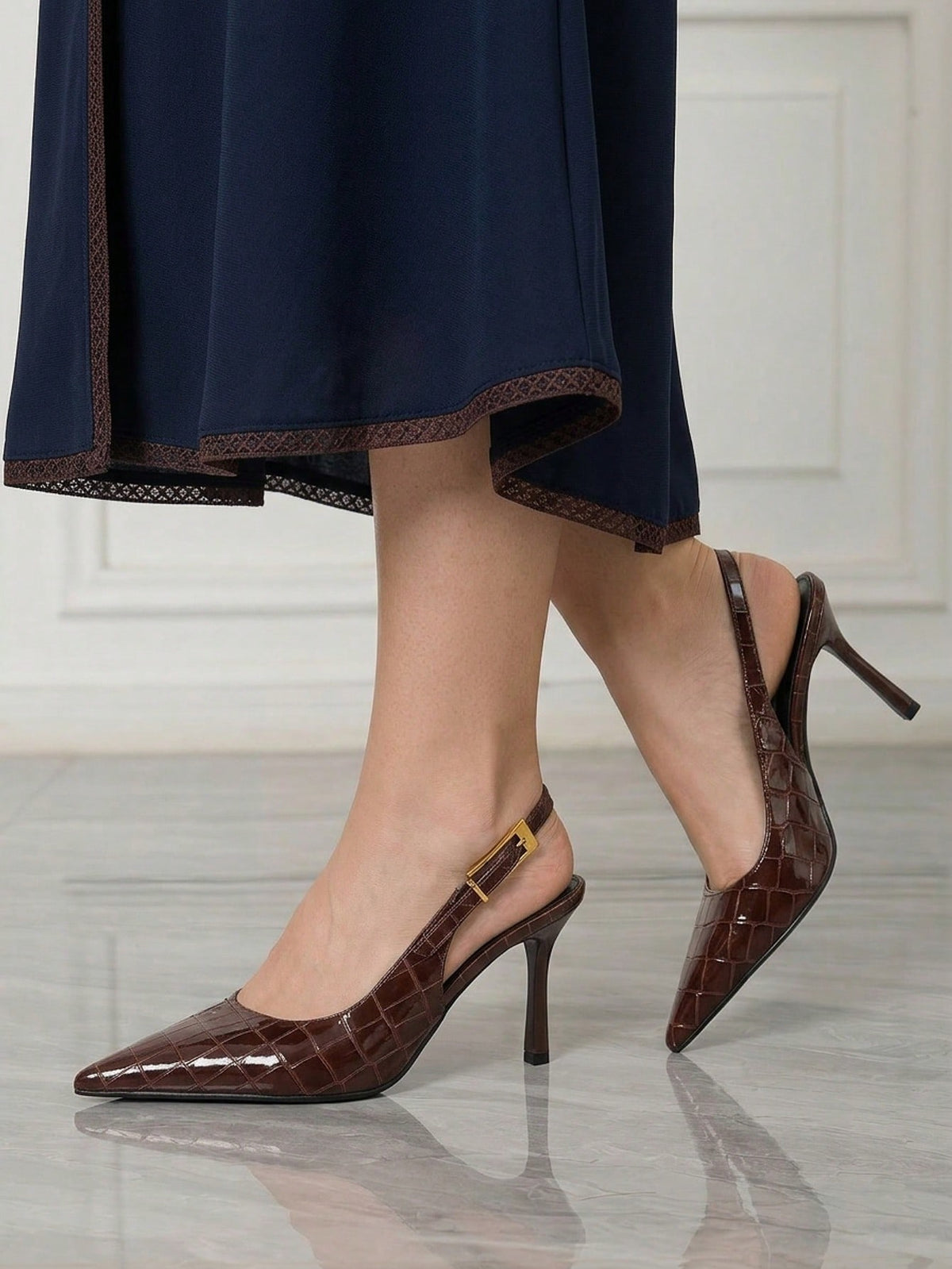 Women's pointed-toe high heel pumps in black mirror PU leather with an ankle strap, stiletto heel, and rhinestone buckle.