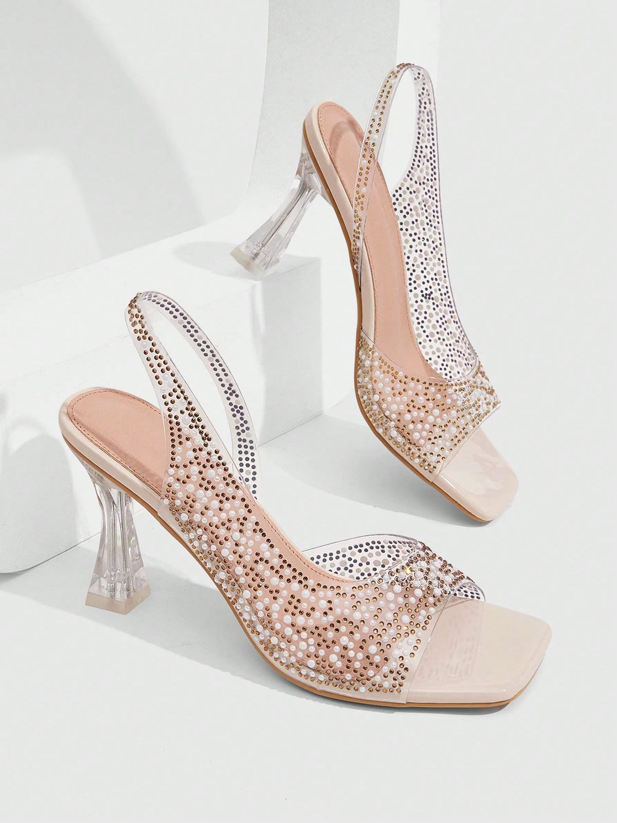 Women's square toe heeled sandals with clear straps, sparkling rhinestone embellishments, and a high pyramid heel.