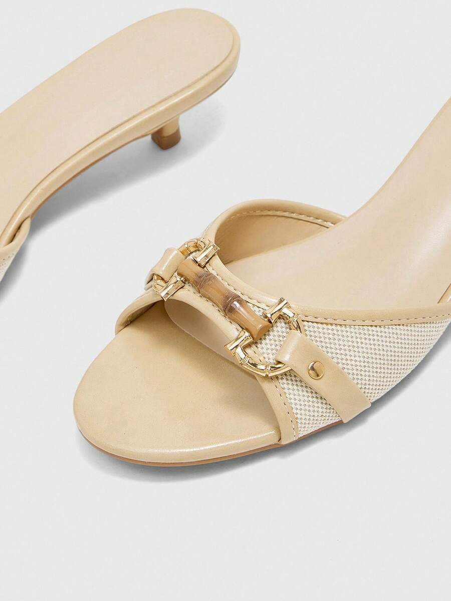 Beige women's slip-on kitten heel slide sandals featuring an accent buckle with grommet eyelets.