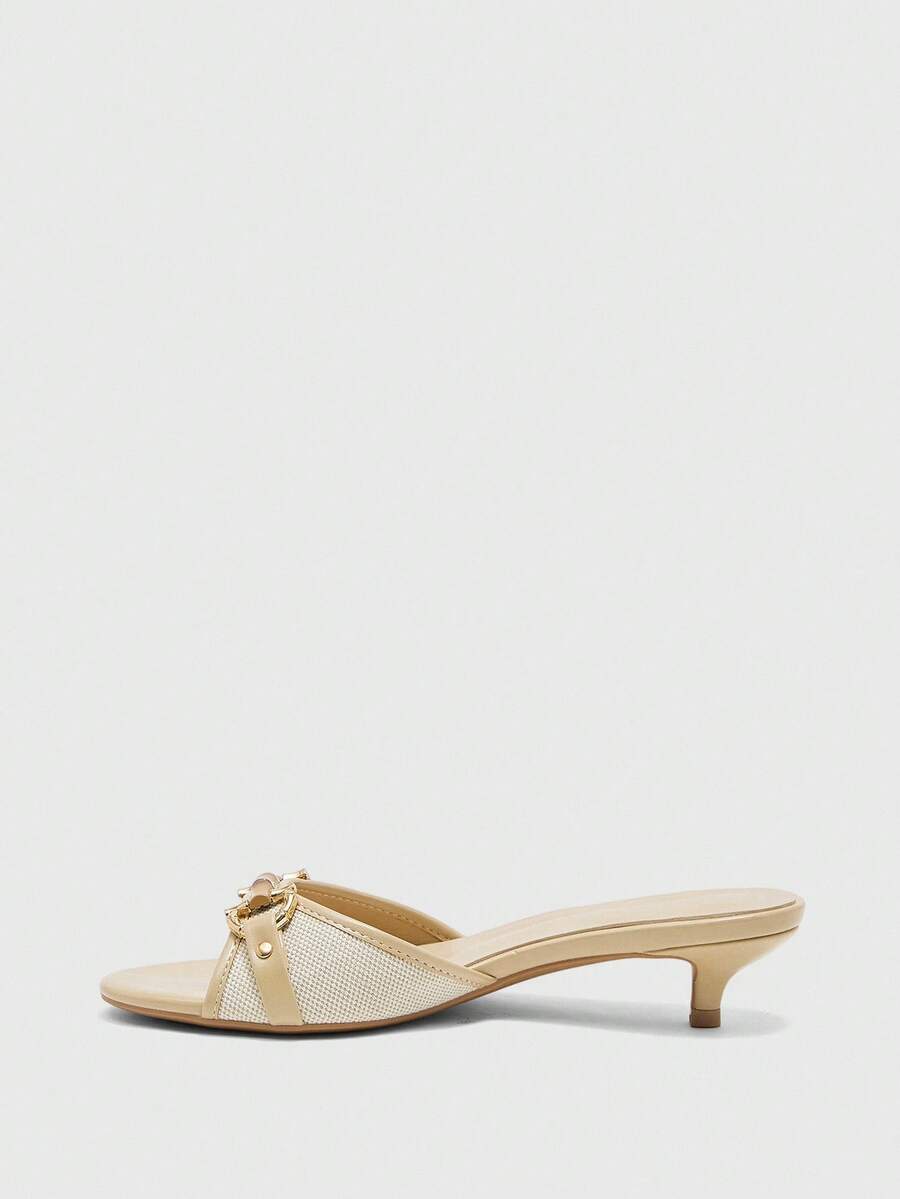 Beige women's slip-on kitten heel slide sandals featuring an accent buckle with grommet eyelets.