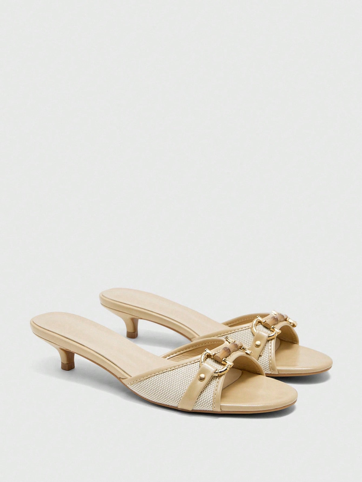 Beige women's slip-on kitten heel slide sandals featuring an accent buckle with grommet eyelets.
