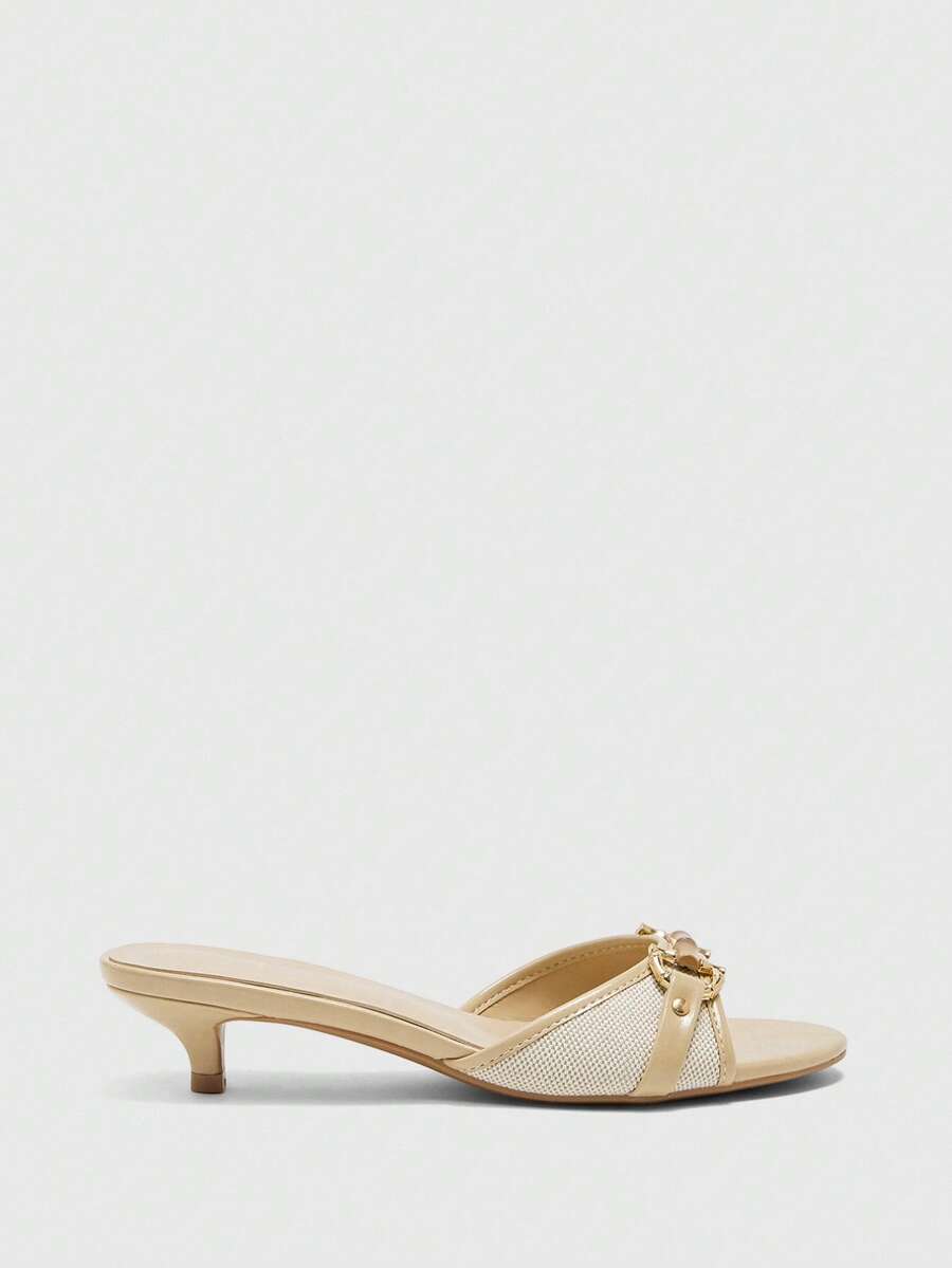 Beige women's slip-on kitten heel slide sandals featuring an accent buckle with grommet eyelets.