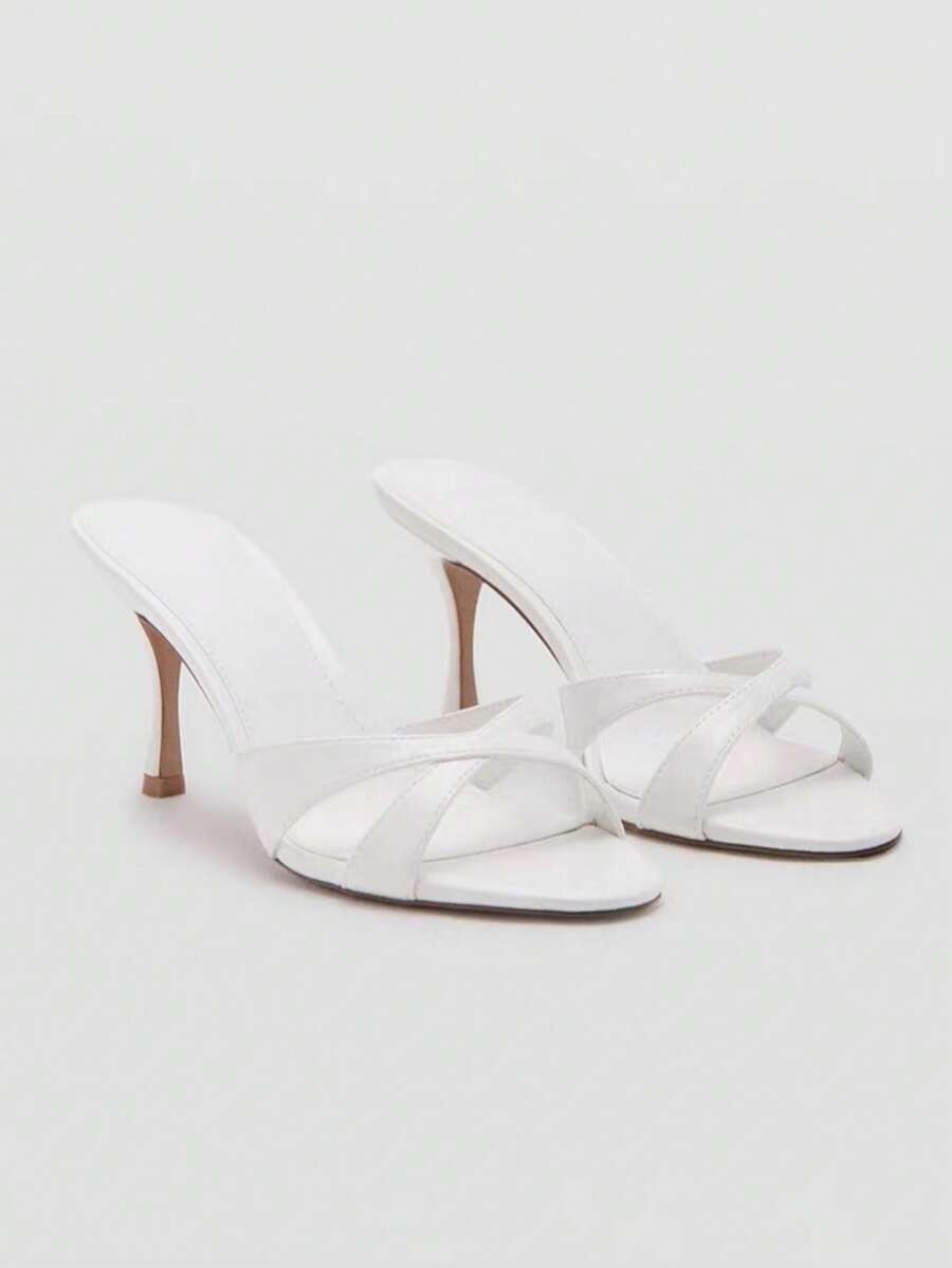 Pair of women's open toe patent leather mule shoes with sleek stiletto heels and cut-out styling