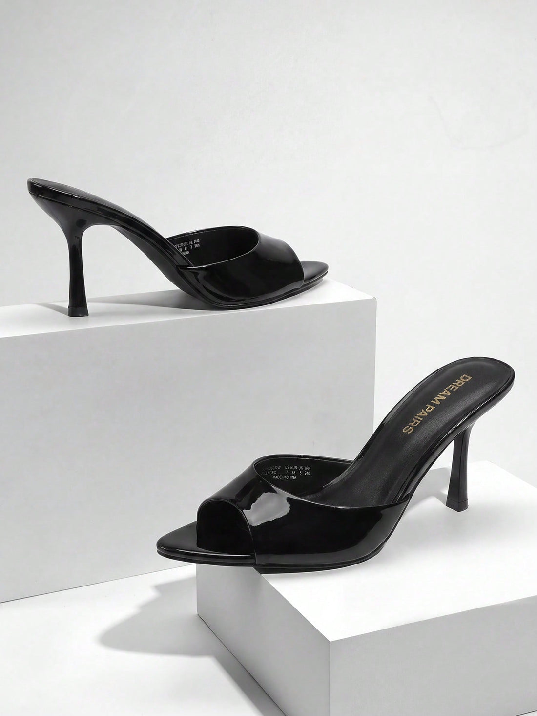 Women's pointed peep toe high heel sandals featuring a sleek stiletto heel, slip-on mule design, and smooth faux leather finish.
