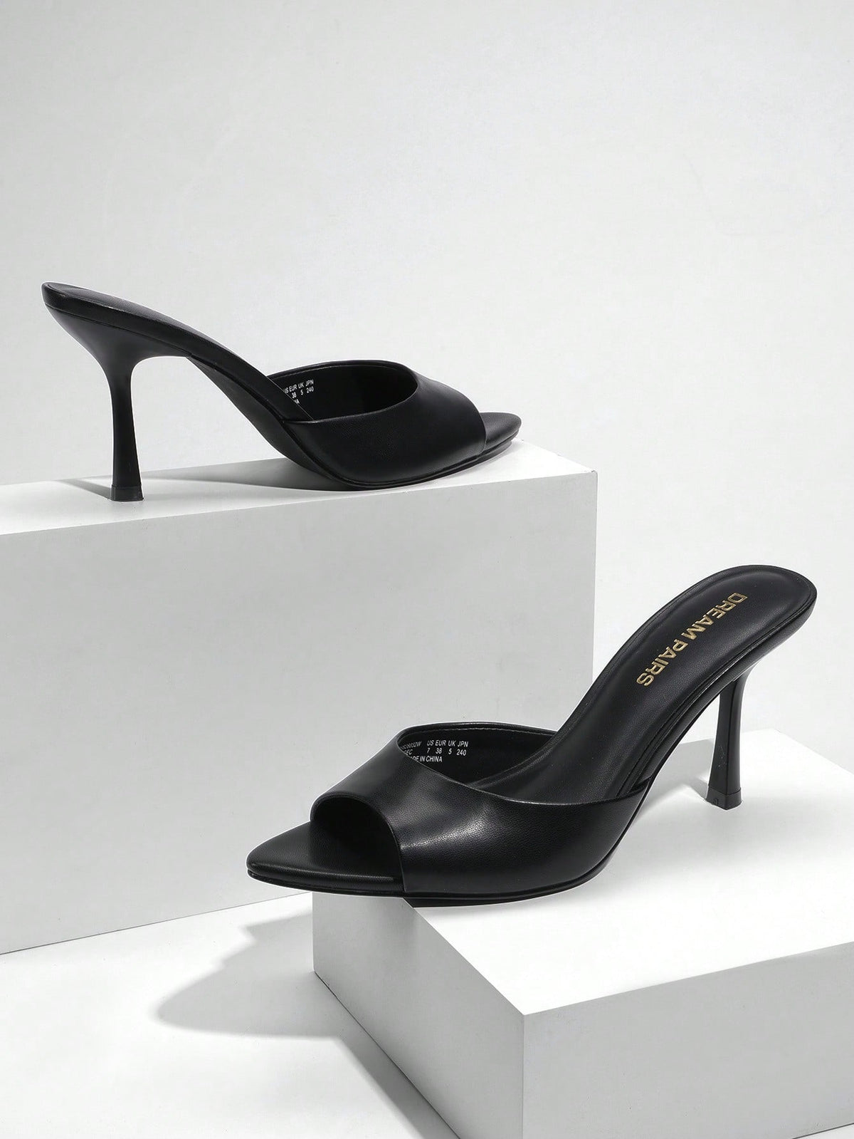 Women's pointed peep toe high heel sandals featuring a sleek stiletto heel, slip-on mule design, and smooth faux leather finish.