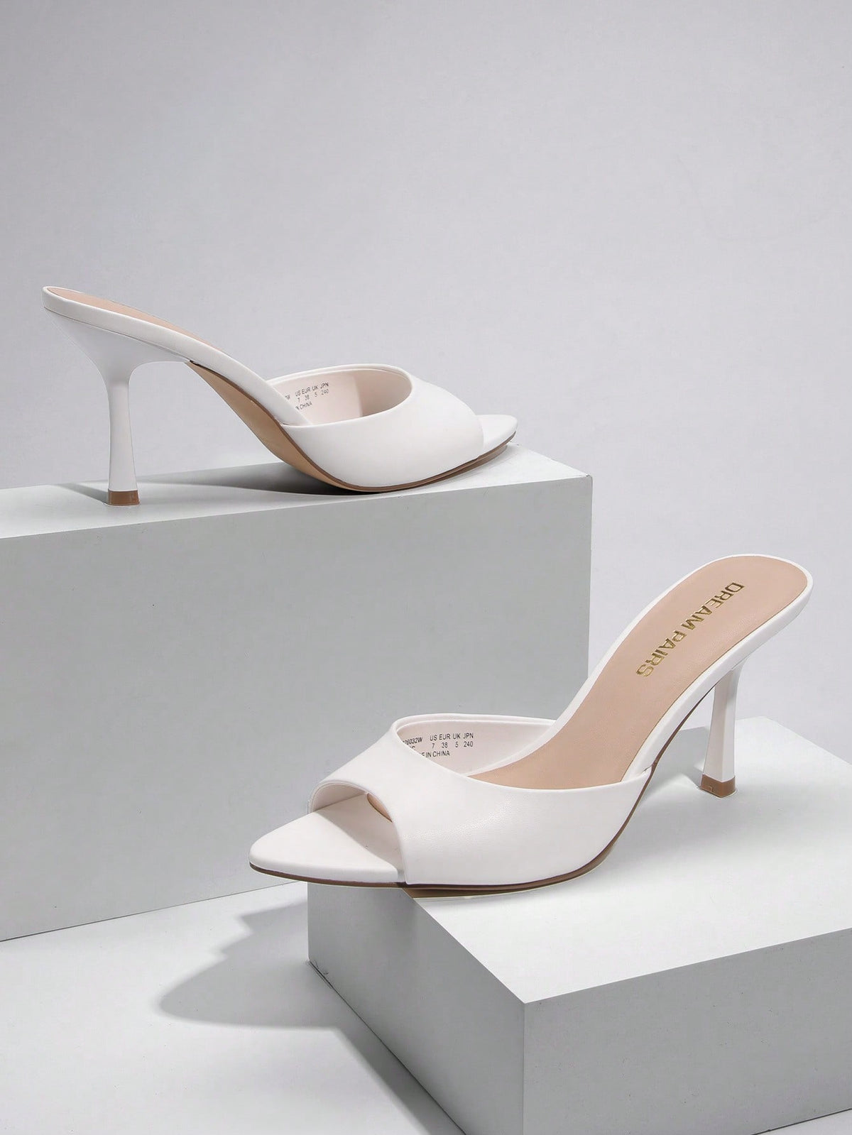 Women's pointed peep toe high heel sandals featuring a sleek stiletto heel, slip-on mule design, and smooth faux leather finish.