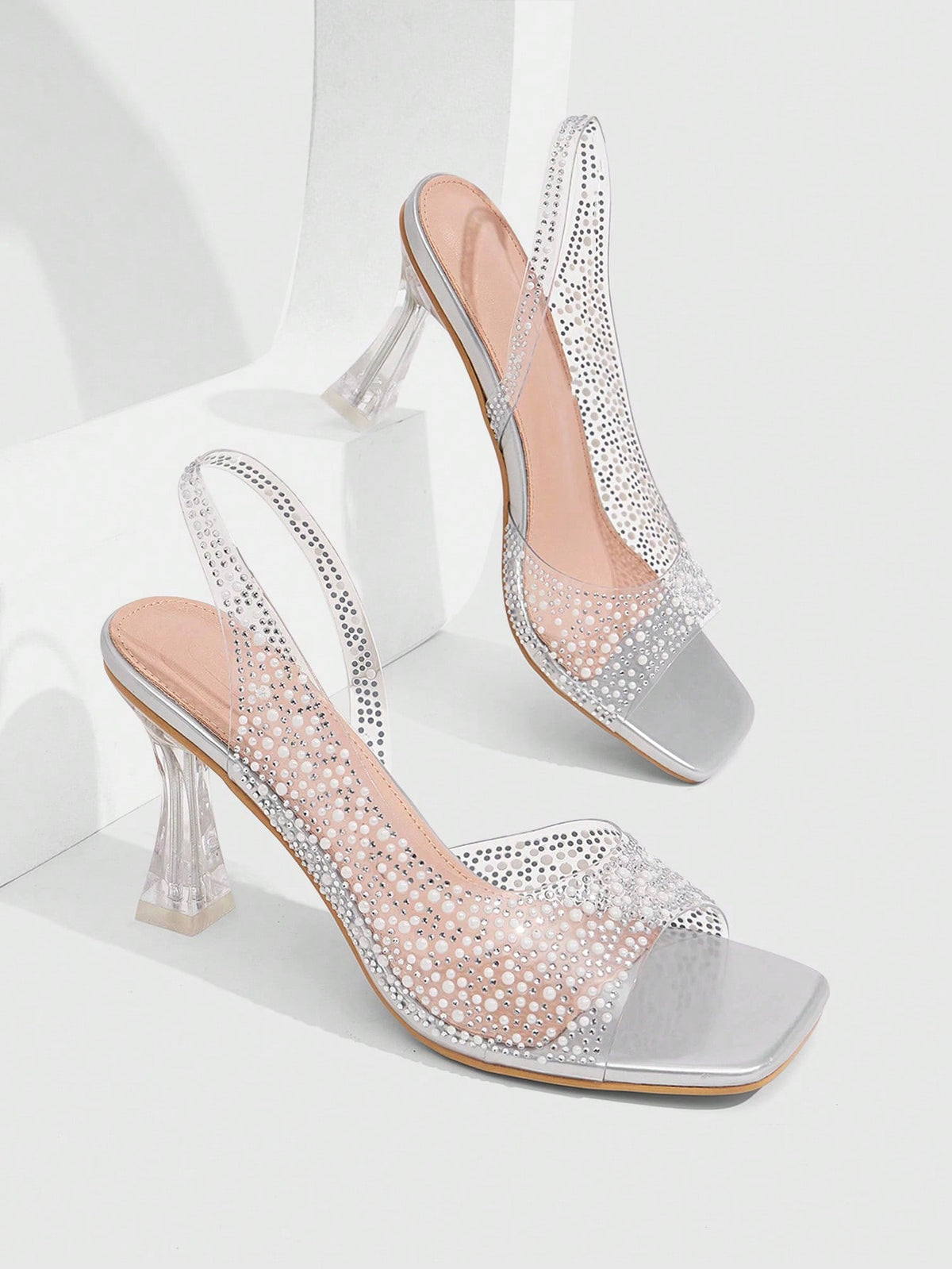 Women's square toe heeled sandals with clear straps, sparkling rhinestone embellishments, and a high pyramid heel.