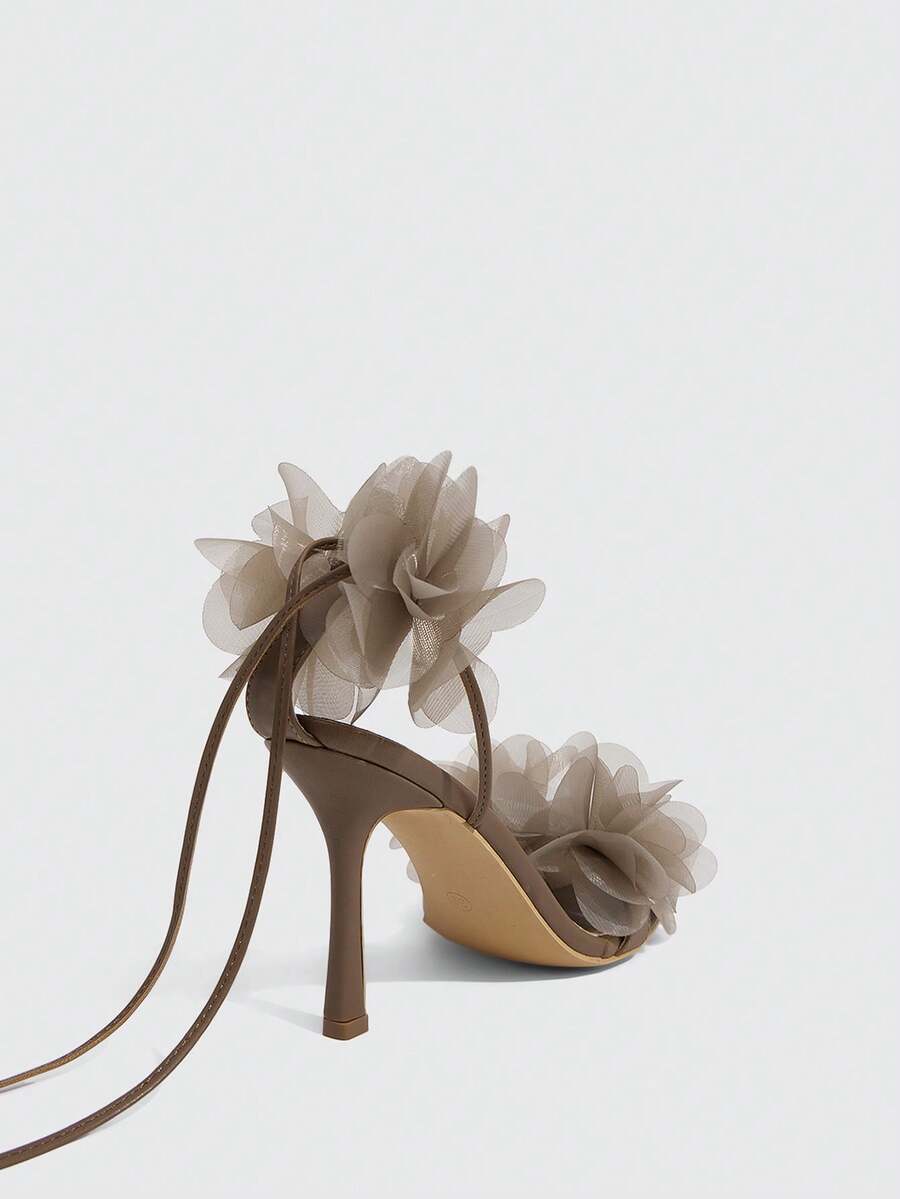 Women's open toe heeled sandals featuring 3D floral decor, satin lace-up ankle straps, and stiletto high heels.