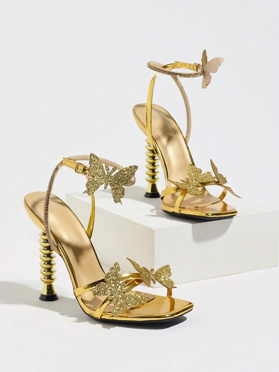 Women's gold high heel sandals featuring open toe, stiletto heel, bow accent, and adjustable ankle strap.