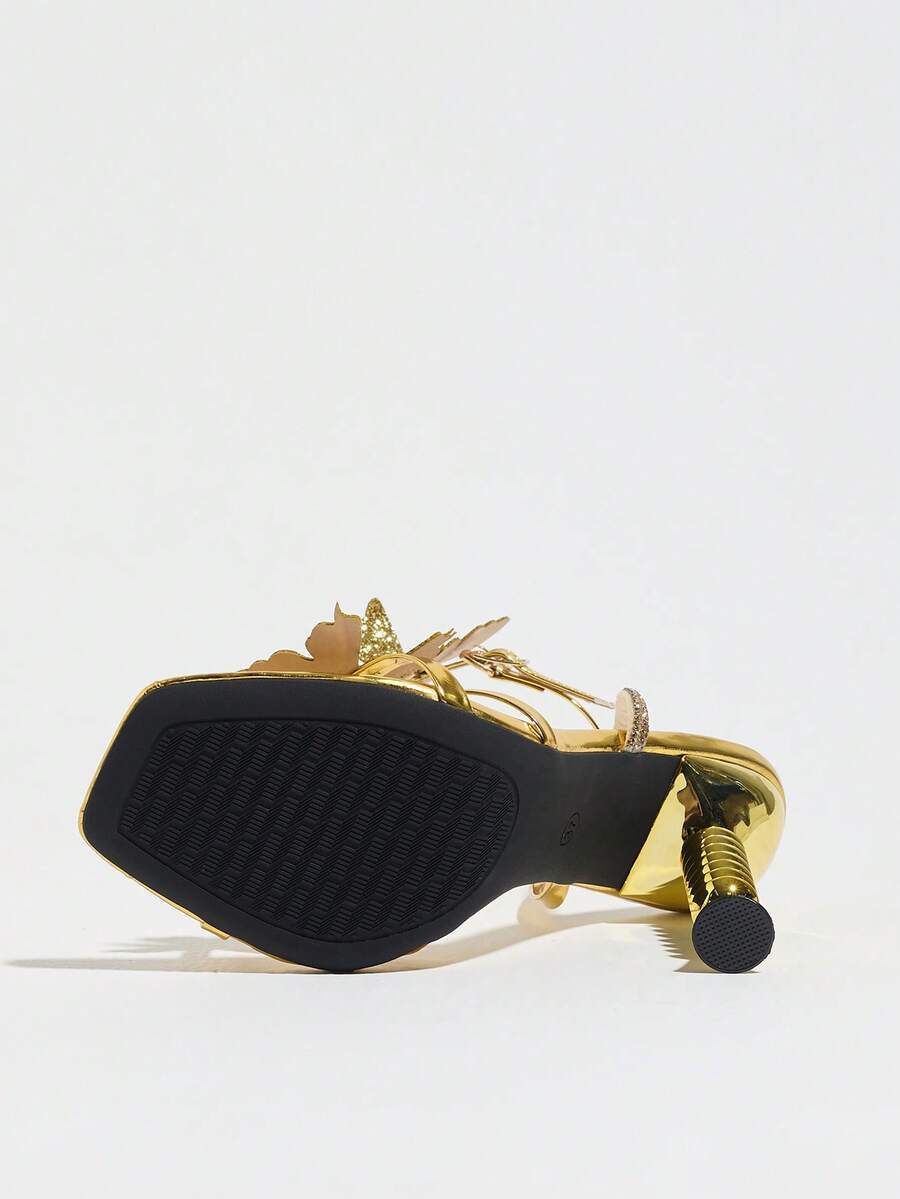 Women's gold high heel sandals featuring open toe, stiletto heel, bow accent, and adjustable ankle strap.