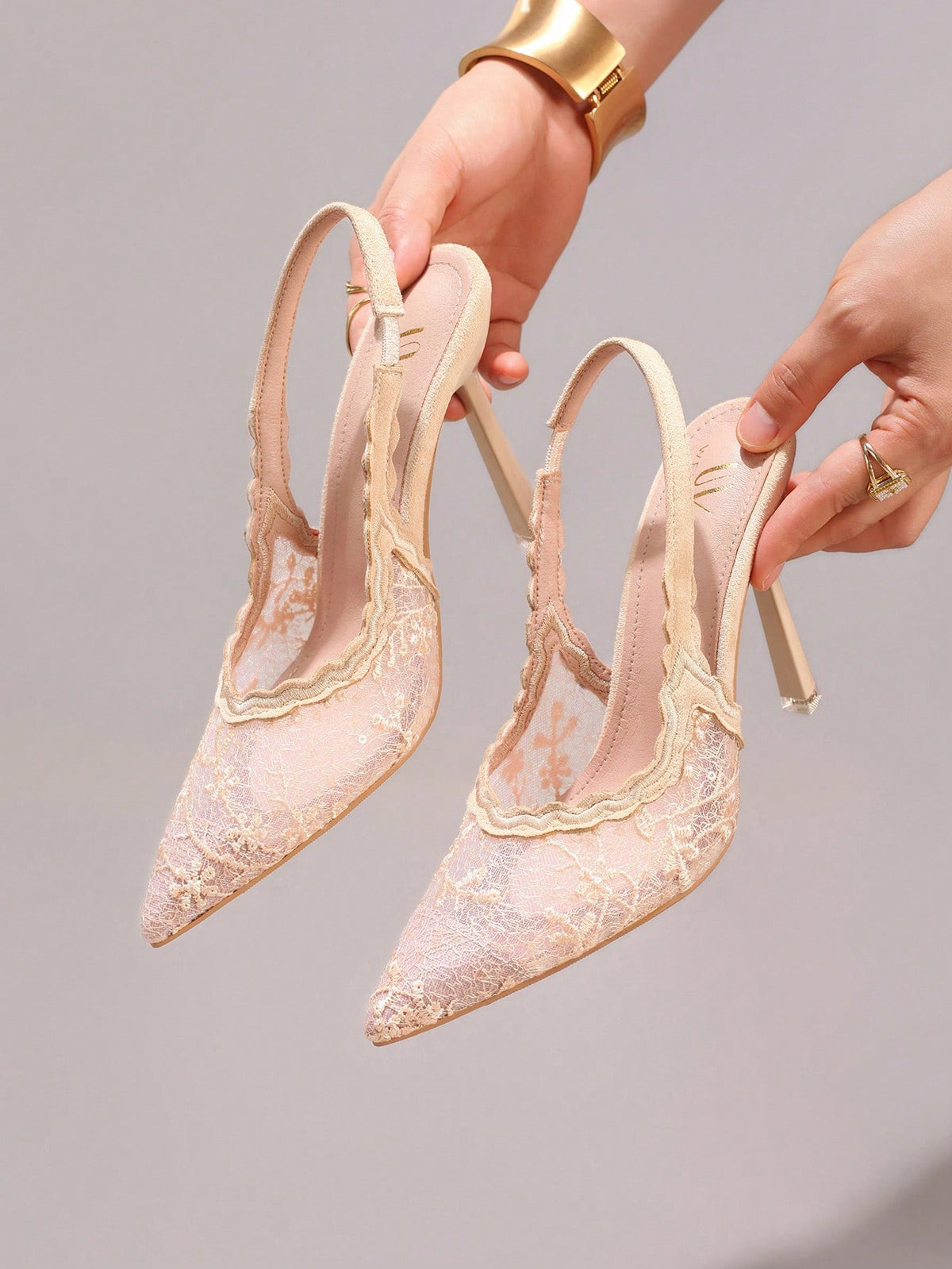 Lace embroidered high heels with thin stiletto heel, pointed toe, rhinestone embellishments, and ankle strap buckle closure.