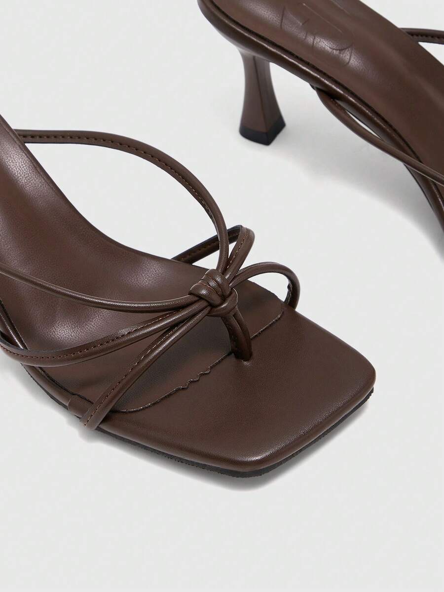 Square toe stiletto heel thong sandals for women featuring thin toe post strap, knot detail, and mid pyramid heel.