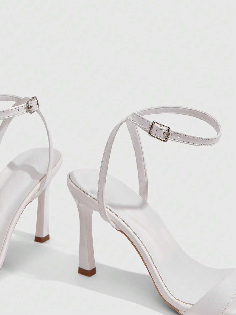 Women's high heel ankle strap sandals with open toe and stiletto heel in mirror black finish.
