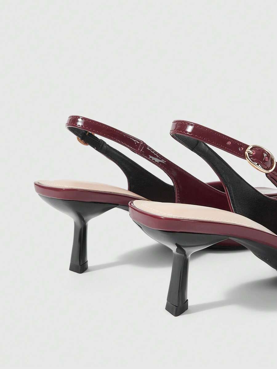 Women's pointed-toe high heel pumps in black mirror PU leather with an ankle strap, stiletto heel, and rhinestone buckle.