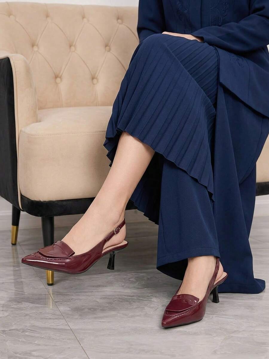 Women's pointed-toe high heel pumps in black mirror PU leather with an ankle strap, stiletto heel, and rhinestone buckle.