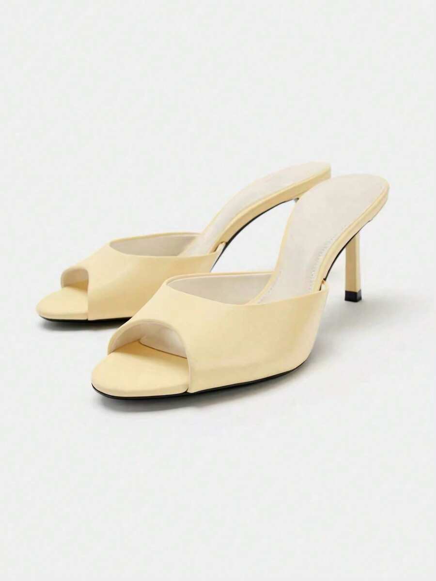 Pair of women's open toe patent leather mule shoes with sleek stiletto heels and cut-out styling