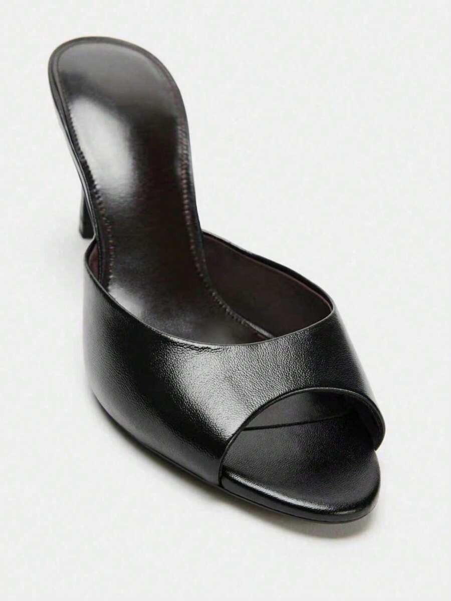 Pair of women's open toe patent leather mule shoes with sleek stiletto heels and cut-out styling