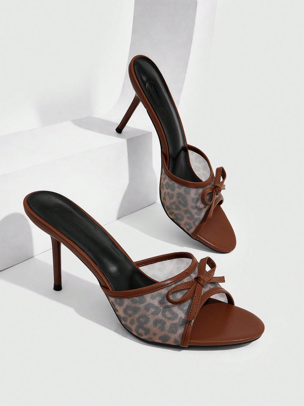 Women's open-toe leopard print mesh stiletto heeled sandals with bow detail.