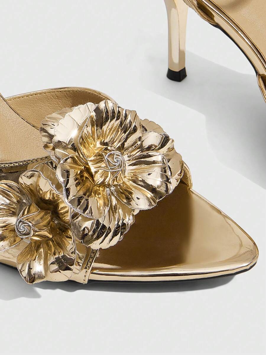 Champagne stiletto high heel sandals featuring a flower detail, open toe, and buckle back strap.