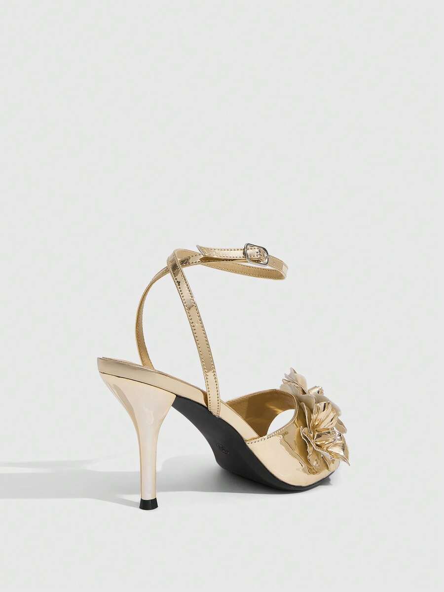 Champagne stiletto high heel sandals featuring a flower detail, open toe, and buckle back strap.