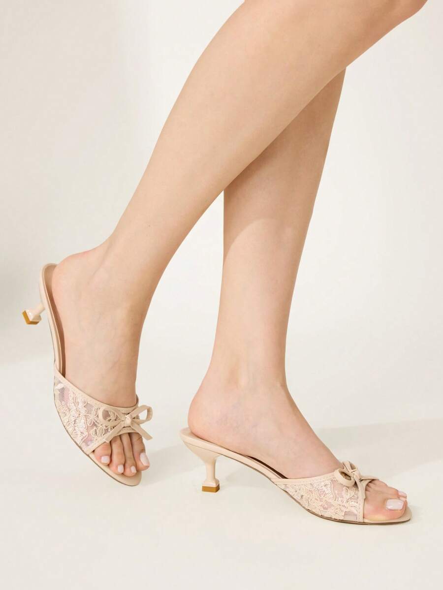 Open toe high heel slide sandals featuring lace details and a bow accent on the upper strap.
