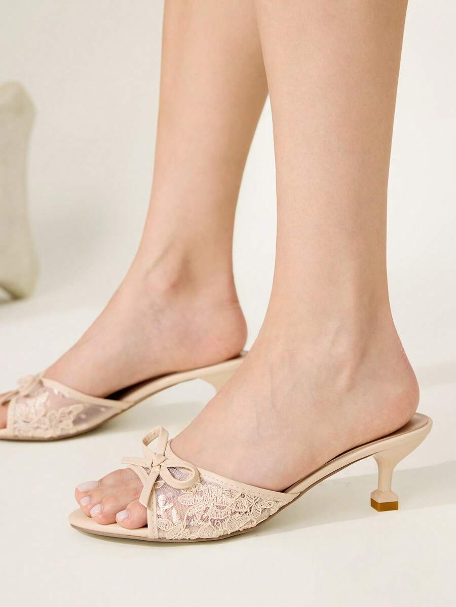 Open toe high heel slide sandals featuring lace details and a bow accent on the upper strap.
