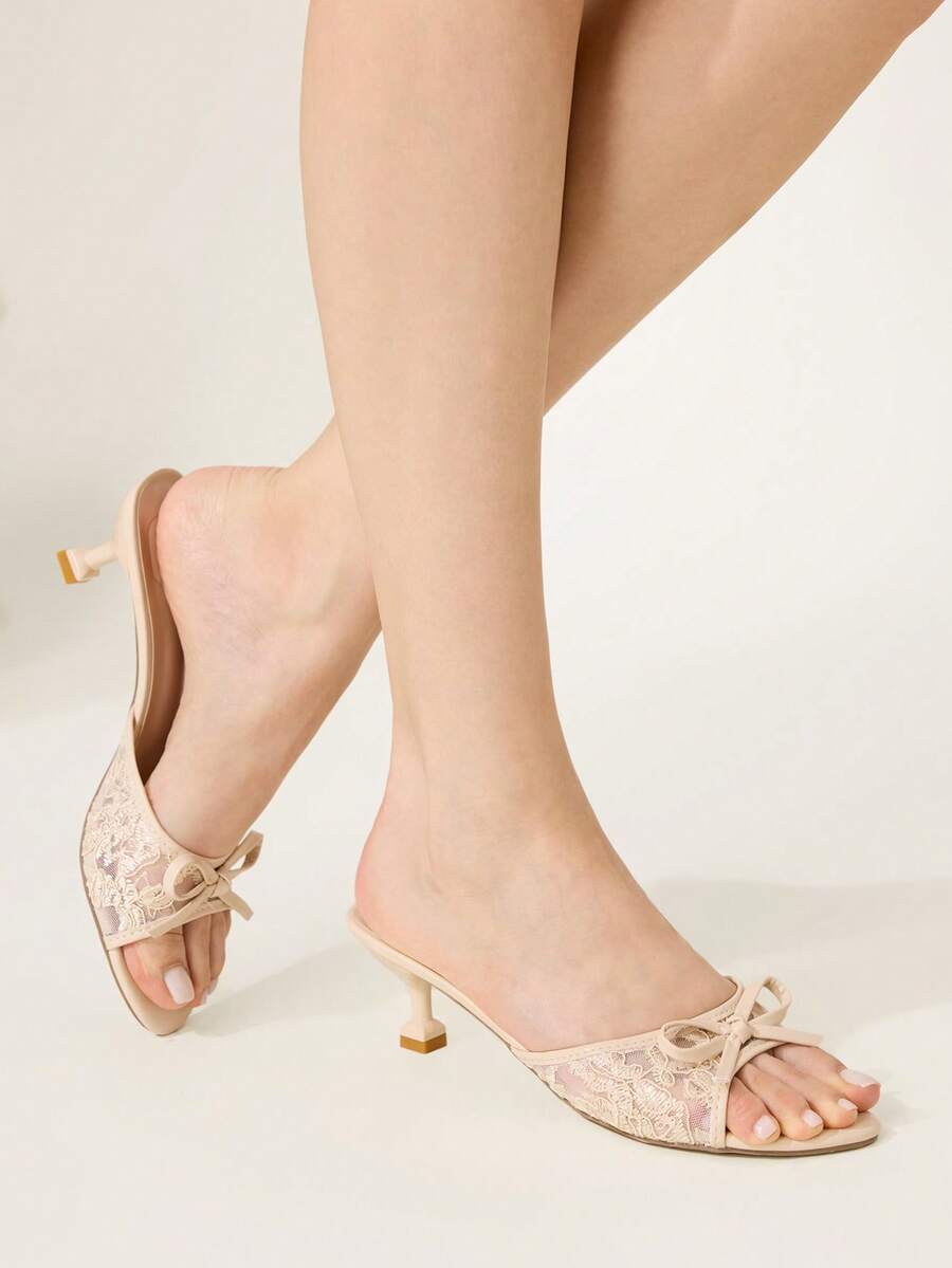 Open toe high heel slide sandals featuring lace details and a bow accent on the upper strap.