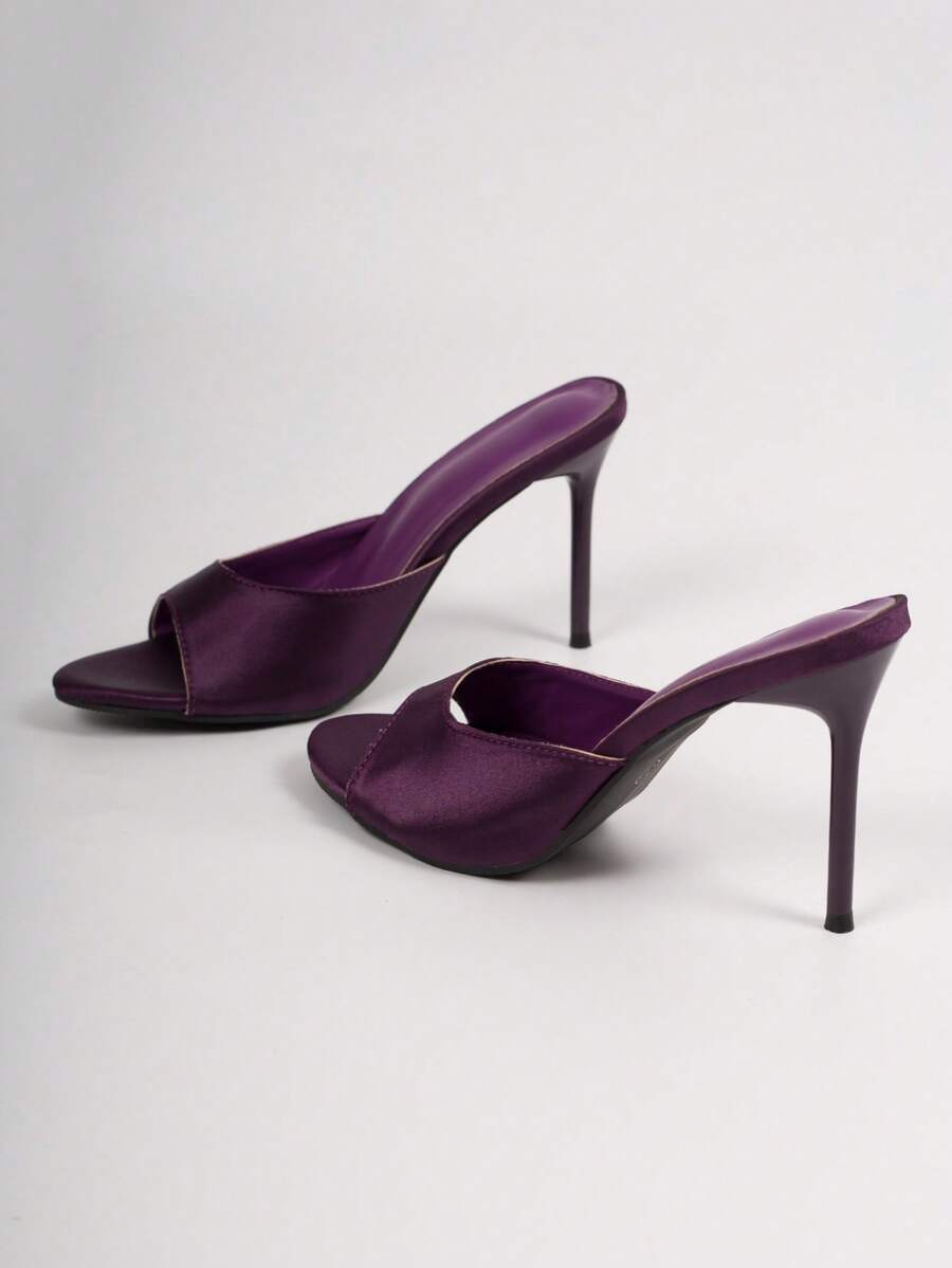 Pair of women's open toe patent leather mule shoes with sleek stiletto heels and cut-out styling