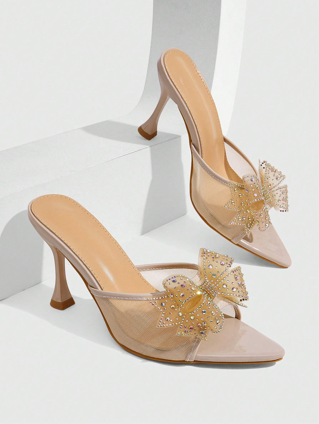 Pair of women's pointed toe stiletto mule sandals with shiny patent upper and slip-on design.