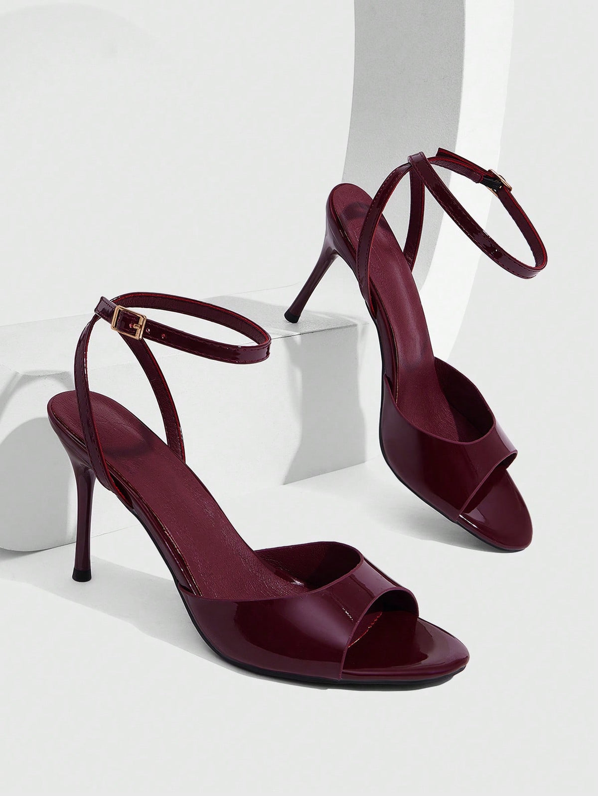 Women's patent leather stiletto sandals with open toe and ankle buckle strap