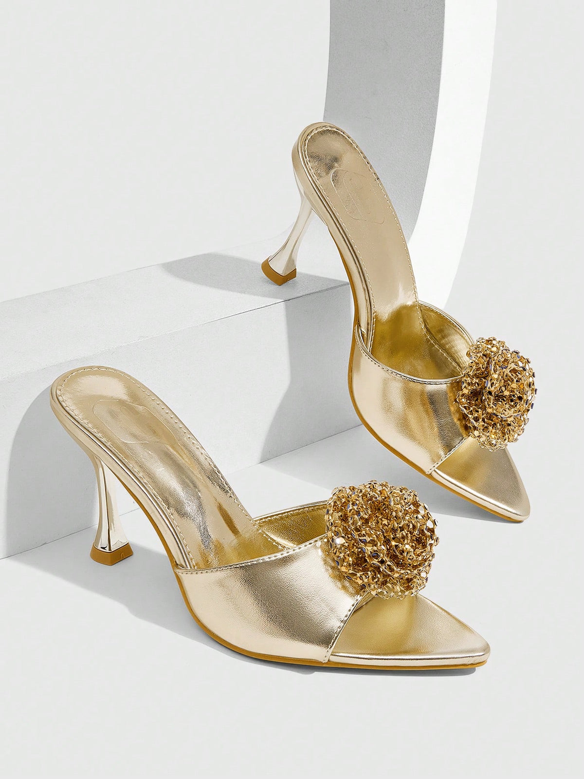 Pair of women's pointed toe stiletto mule sandals with shiny patent upper and slip-on design.
