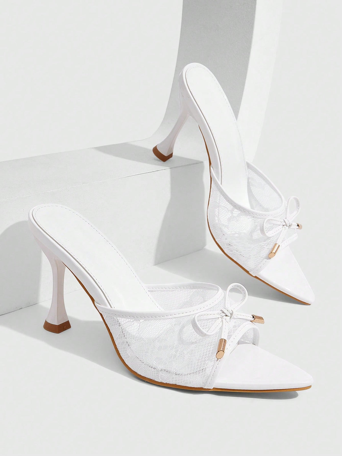 Pair of women's pointed toe stiletto mule sandals with shiny patent upper and slip-on design.