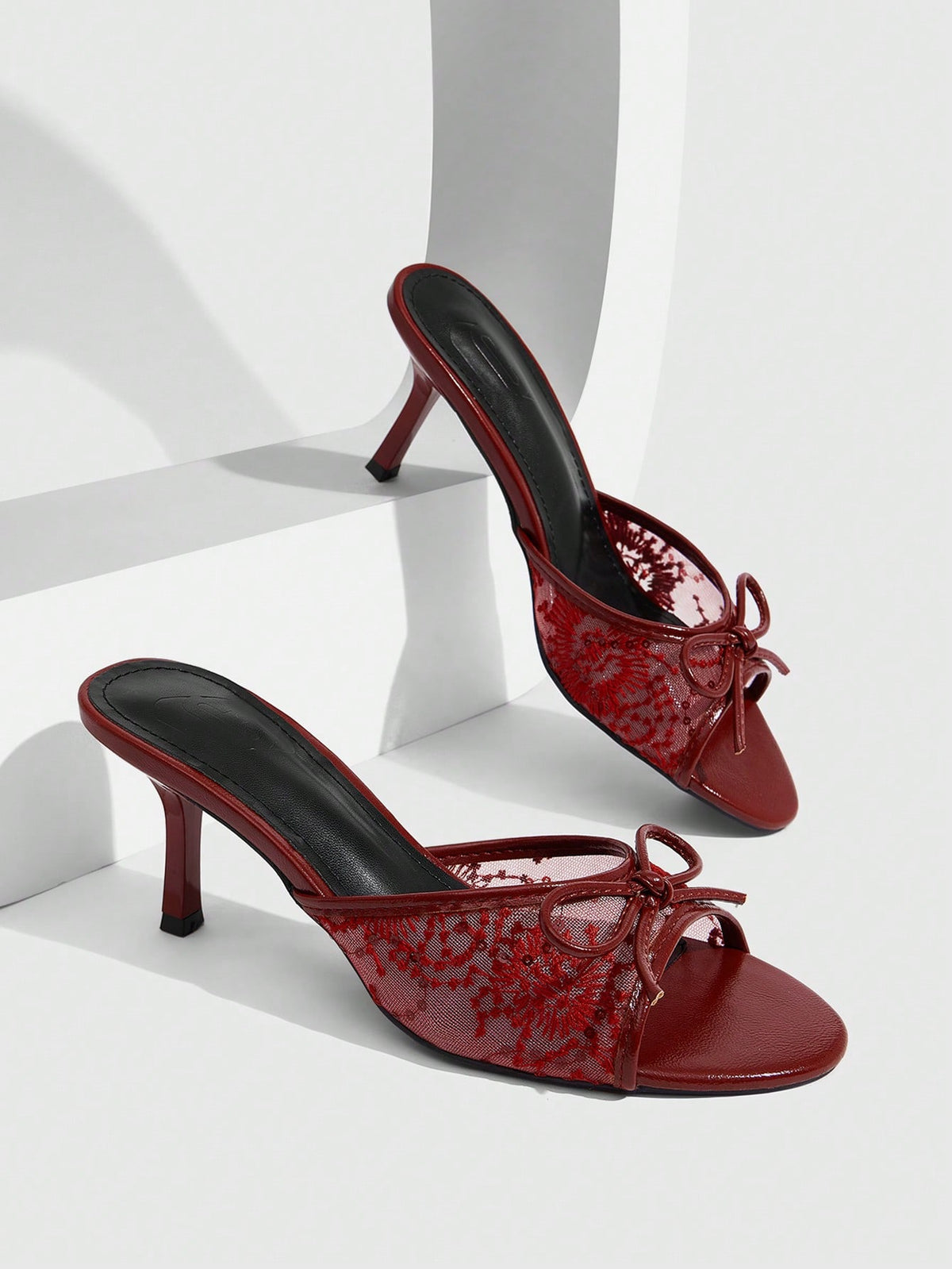 Open toe high heel slide sandals featuring lace details and a bow accent on the upper strap.