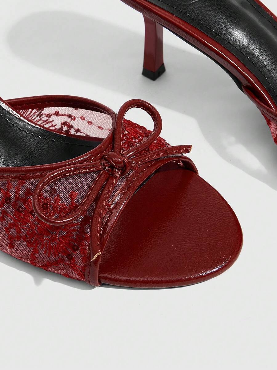 Open toe high heel slide sandals featuring lace details and a bow accent on the upper strap.