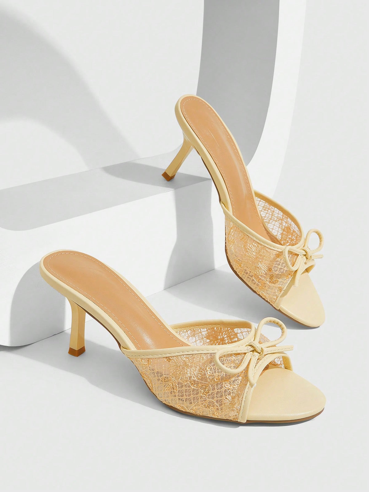 Open toe high heel slide sandals featuring lace details and a bow accent on the upper strap.