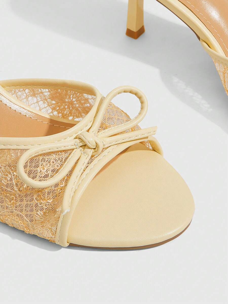 Open toe high heel slide sandals featuring lace details and a bow accent on the upper strap.
