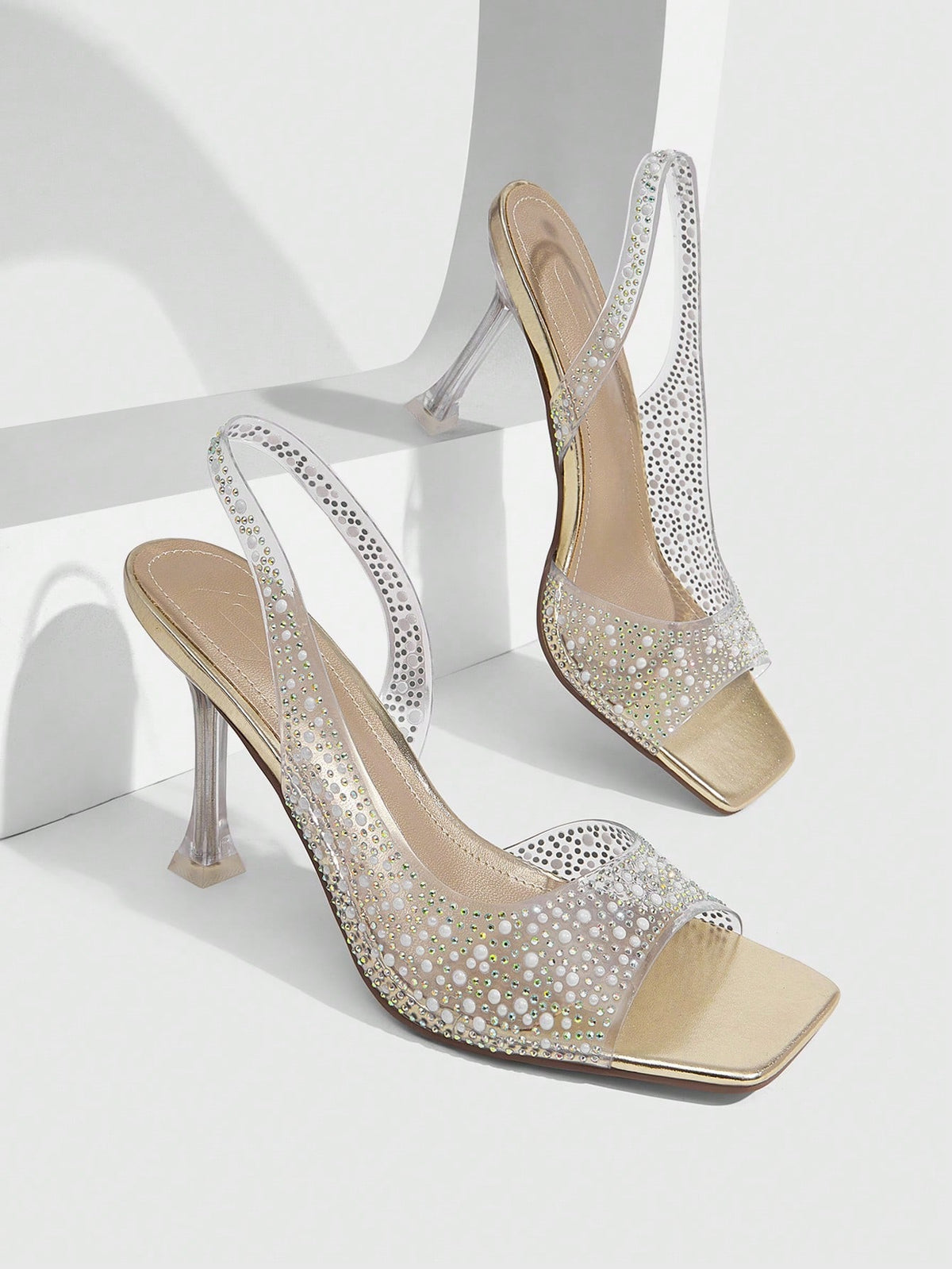 Women's square toe heeled sandals with clear straps, sparkling rhinestone embellishments, and a high pyramid heel.