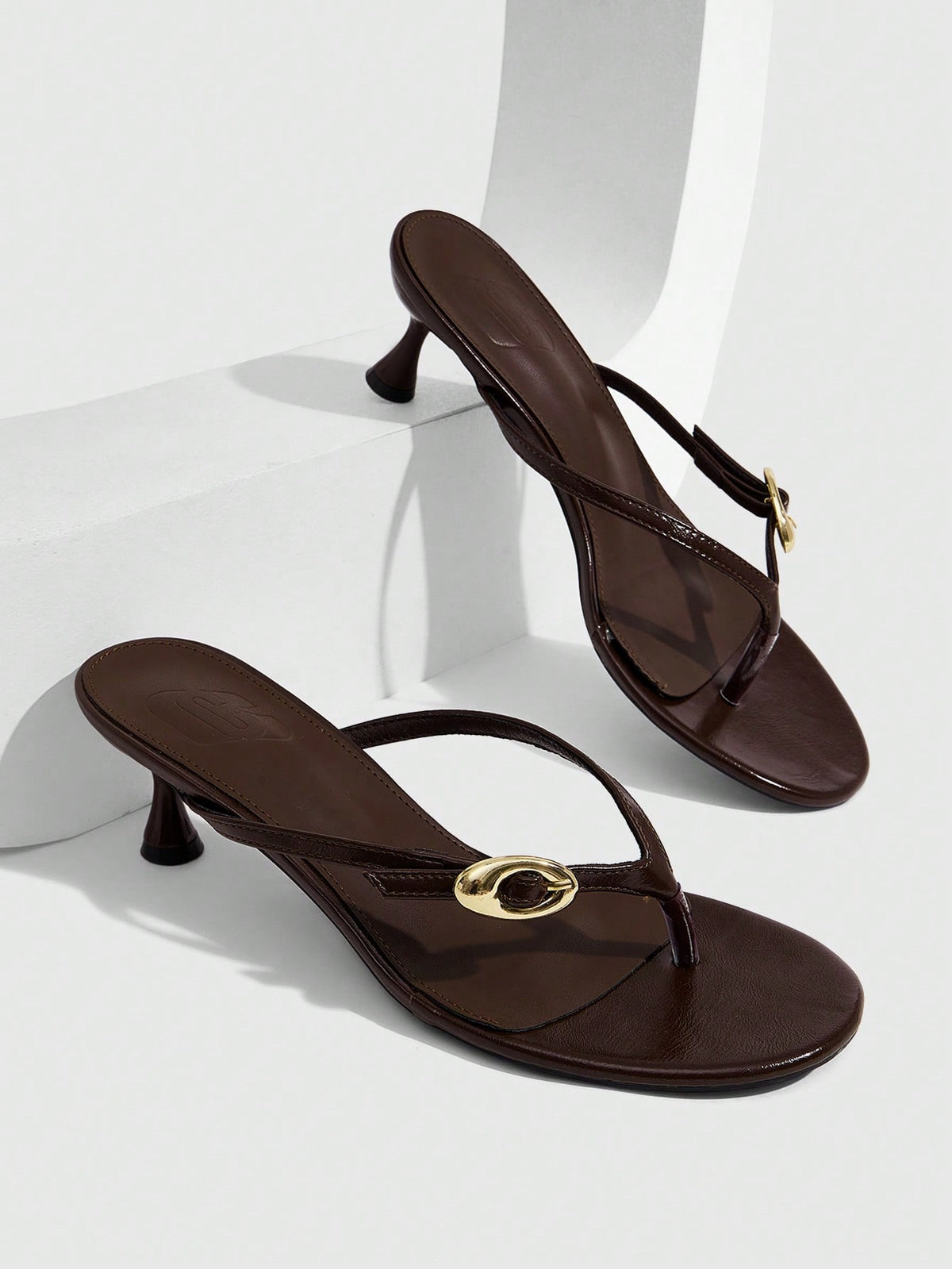 Women's slingback heeled sandals featuring a button toe post accent, sleek mid pyramid heel, and smooth faux leather finish.