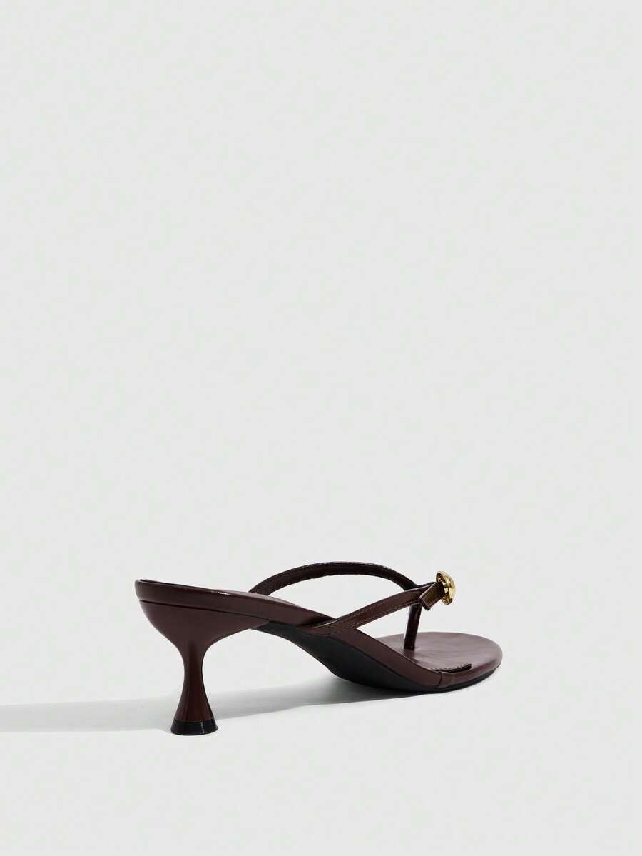 Women's slingback heeled sandals featuring a button toe post accent, sleek mid pyramid heel, and smooth faux leather finish.