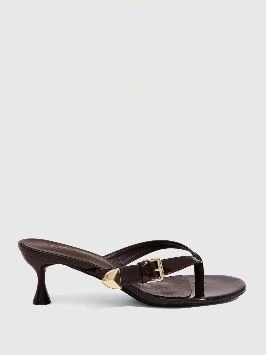 Women's patent leather heeled sandals featuring a toe post strap with metal buckle and mid pyramid heel.