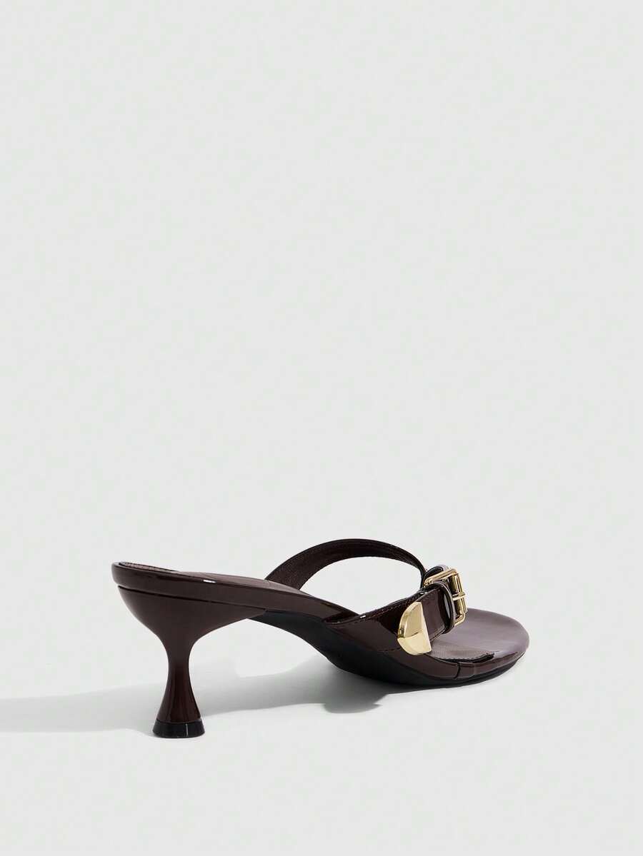 Women's patent leather heeled sandals featuring a toe post strap with metal buckle and mid pyramid heel.
