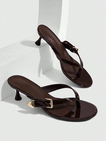 Women's patent leather heeled sandals featuring a toe post strap with metal buckle and mid pyramid heel.